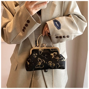 Dettaglio della borsa vintage nera con ricami di farfalle dorate e manico in metallo