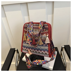 Dettaglio borsa a secchiello boho intrecciata con nappe colorate e ampia tracolla a motivi