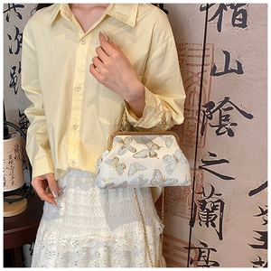 Dettaglio della borsa cheongsam stile vintage con ricamo farfalla dorata e manico perla