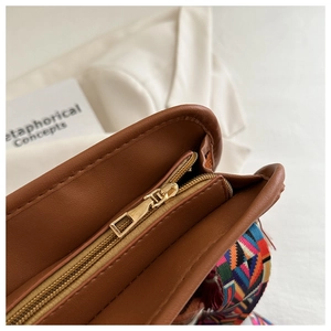 Dettaglio borsa in pelle marrone con cerniera dorata e tracolla in tessuto colorato