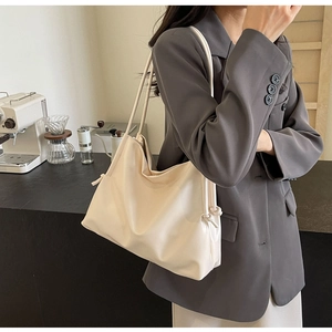 Dettaglio della borsa tote in ecopelle crema con eleganti nodi laterali decorativi