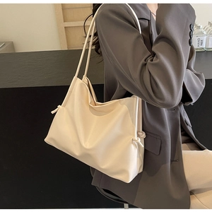 Macro detail of the side drawstring knot on an ivory faux leather large tote handbag