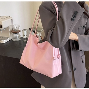 Pink oversized tote bag detail featuring knot accents and soft shoulder straps worn by model