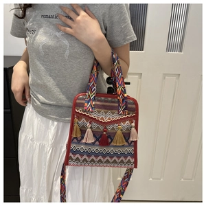 Dettaglio di borsa a secchiello etnica intrecciata con nappe colorate e tracolla a motivi