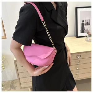 Sacoche demi-lune rose avec chaîne dorée portée sur une robe blazer noire chic