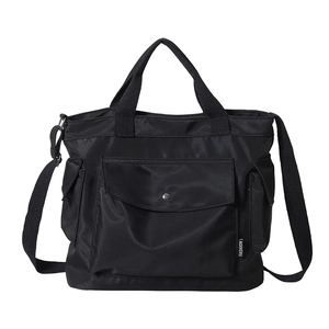 Minimalist black nylon tote bag with large front pocket and adjustable shoulder strap