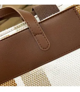 Dettaglio macro di cuciture precise su tela pregiata e pelle marrone della borsa tote
