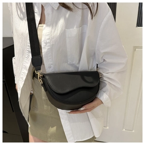 Détail du sac besace noir minimaliste avec boucle dorée et large bandoulière en tissu