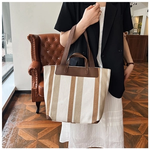 Vista dettagliata della borsa tote in tela a righe marroni e bianche con manici in pelle