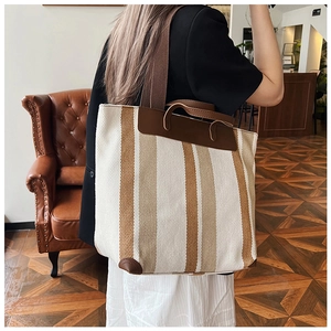Borsa tote in tela a righe con manici in pelle indossata a tracolla da una modella