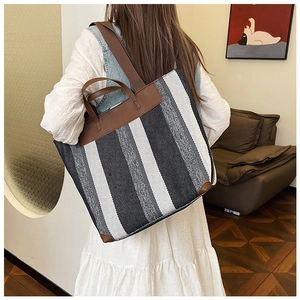 Dettaglio di una grande borsa tote in tela a righe con manici in pelle marrone su modella