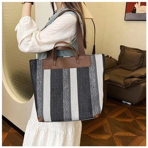 Dettaglio della borsa tote in tela con finiture in pelle marrone e motivo a strisce
