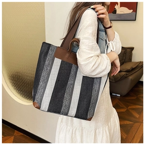 Dettaglio della borsa tote in tela a righe con angoli in pelle e ampi spallacci marroni