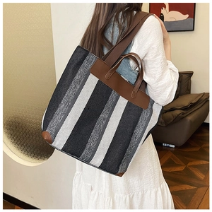 Dettaglio della borsa tote grande in tela a righe con finiture e manici in pelle marrone
