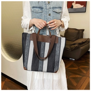Vista dettagliata della borsa tote a righe con finiture in pelle marrone e manici