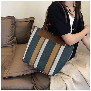 Dettaglio della grande borsa tote intrecciata a righe con manici in pelle e spazio interno