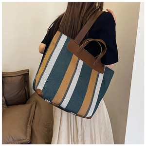 Dettaglio della grande borsa tote a righe con texture intrecciata verde e bianca e manici in pelle