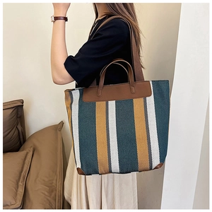 Dettaglio della grande borsa tote in tela a righe con manici in pelle marrone scuro