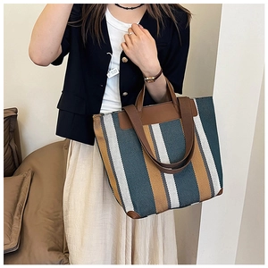 Dettaglio borsa tote in tela a righe retrò con angoli rinforzati in pelle marrone scuro
