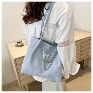 Détail du sac cabas bleu clair avec texture froissée et décoration de chaîne métallique