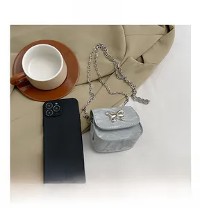 Mini borsa argento con catena a farfalla accanto a uno smartphone per confronto dimensioni