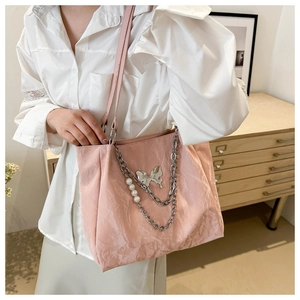 Détail du sac cabas rose avec chaîne argentée, perles blanches et pendentif papillon
