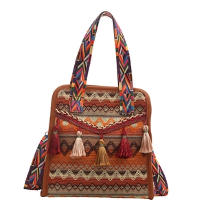Borsa tote etnica bohémien con motivi a onde e nappe colorate su sfondo bianco neutro