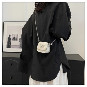 Mini borsa bianca a tracolla con farfalla d'argento indossata da una modella
