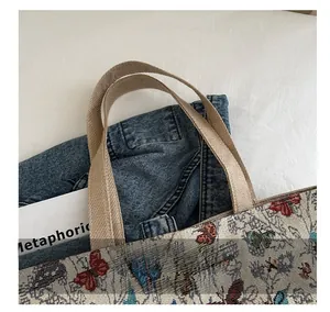 Dettaglio del manico in tela kaki intrecciata su una borsa tote con motivi a farfalla