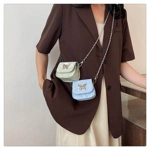 Mini borsa a tracolla con catena a farfalla indossata con giacca marrone e gonna beige