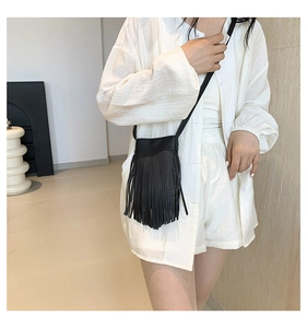 Detail shot of black leather crossbody bag featuring long stylish fringe tassels