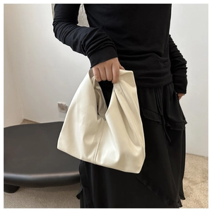 Dettaglio della borsa tote crema minimalista con texture in morbida pelle e pieghe