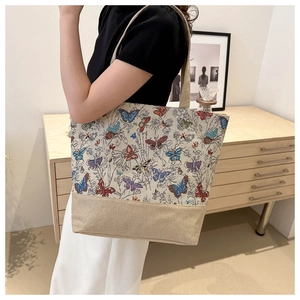 Dettaglio della borsa tote in lino con motivo a farfalla intrecciata e tela beige