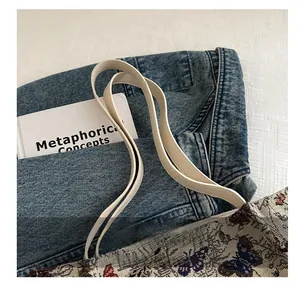 Detailed close-up of butterfly embroidery and cream leather handles on a fabric tote bag