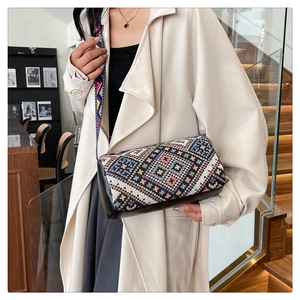 Dettaglio borsa a secchiello boho con motivi geometrici colorati e tracolla in tessuto