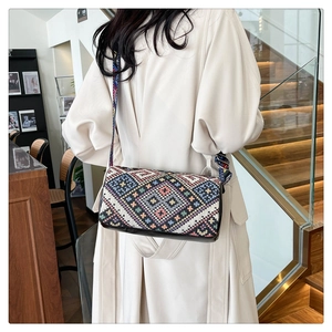 Dettaglio borsa a secchiello boho con trama geometrica e tracolla larga colorata