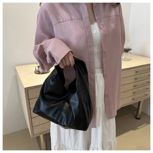 Dettaglio di una borsa tote nuvola nera arricciata con outfit minimal e luce soffusa