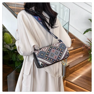 Dettaglio borsa a secchiello boho con motivi geometrici e tracolla in tessuto largo