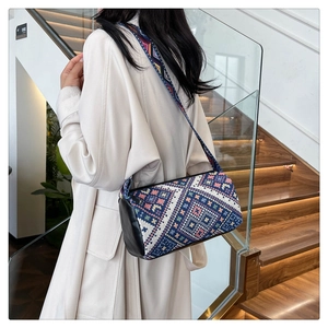 Dettaglio borsa a secchiello etnica con motivi geometrici e tracolla larga su modella