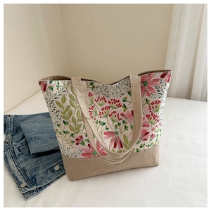 Borsa tote in lino con stampe floreali rosa presentata su un letto bianco