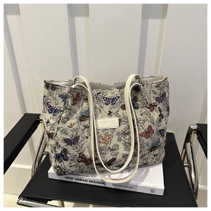 Detail of butterfly pattern jacquard weaving and white leather brand label on tote bag