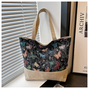 Dettaglio del ricamo a farfalla vintage e della trama patchwork in lino della borsa