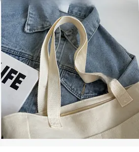 Dettaglio delle cuciture rinforzate e della cerniera sulla borsa tote in tela beige