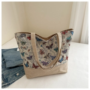 Dettaglio dei motivi a farfalla in jacquard e cuciture in lino della borsa tote