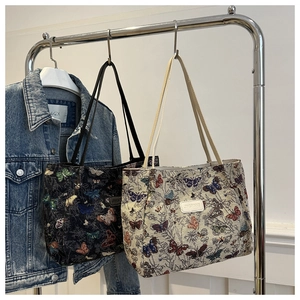 Detail of canvas tote bags with butterfly prints in black and cream on hangers