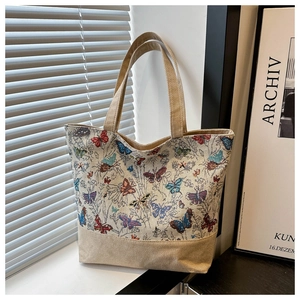 Dettaglio della borsa tote in lino con farfalle colorate sul davanzale soleggiato