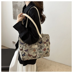 Close-up of butterfly embroidery texture and leather strap on a beige tote bag