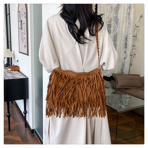 Dettaglio borsa a tracolla boho in camoscio marrone con frange e tracolla intrecciata