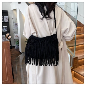 Dettaglio di una borsa a tracolla boho nera con lunghe frange e tracolla in corda tessuta