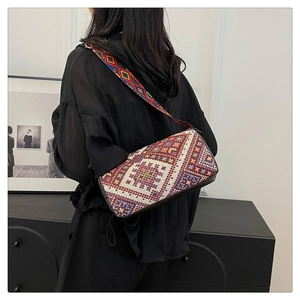 Dettaglio borsa a tracolla con motivi geometrici e tracolla larga indossata da modella